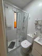 Espejo del lavabo reflejando el toallero con toallas mostaza y el secador de pared
